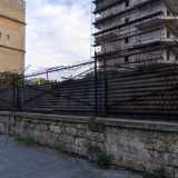 Ci avviciniamo al muro perimetrale, delimitato da blocchi di tufo e da una grata con filo spinato ormai totalmente arrugginita